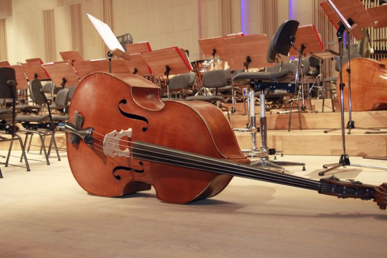 instrumenty muzyczne na scenie w sali koncertowej. Na pierwszym planie leżący kontrabas