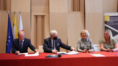 Marszałek Andrzej Bętkowski i wicemarszałek Renata Janik siedzą przy stolez beneficjentami, podpisują umowy