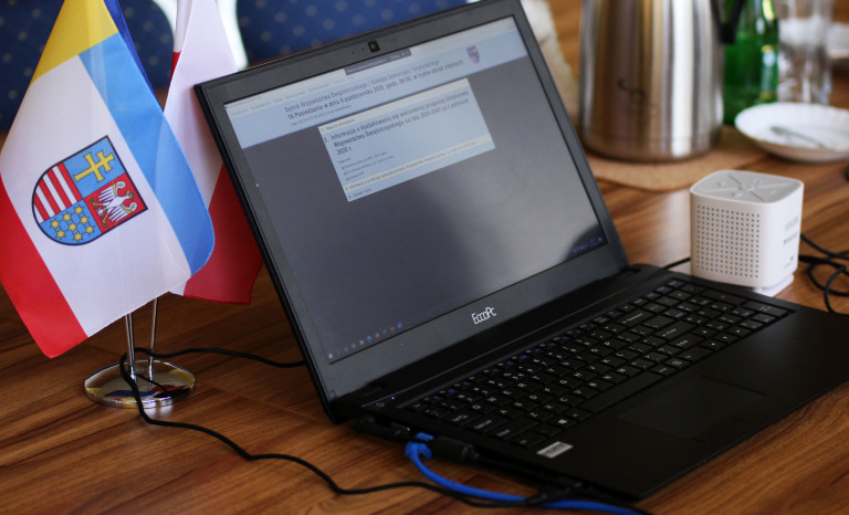 Ekran monitora komputerowego, obok niego flaga województwa świętokrzyskiego.