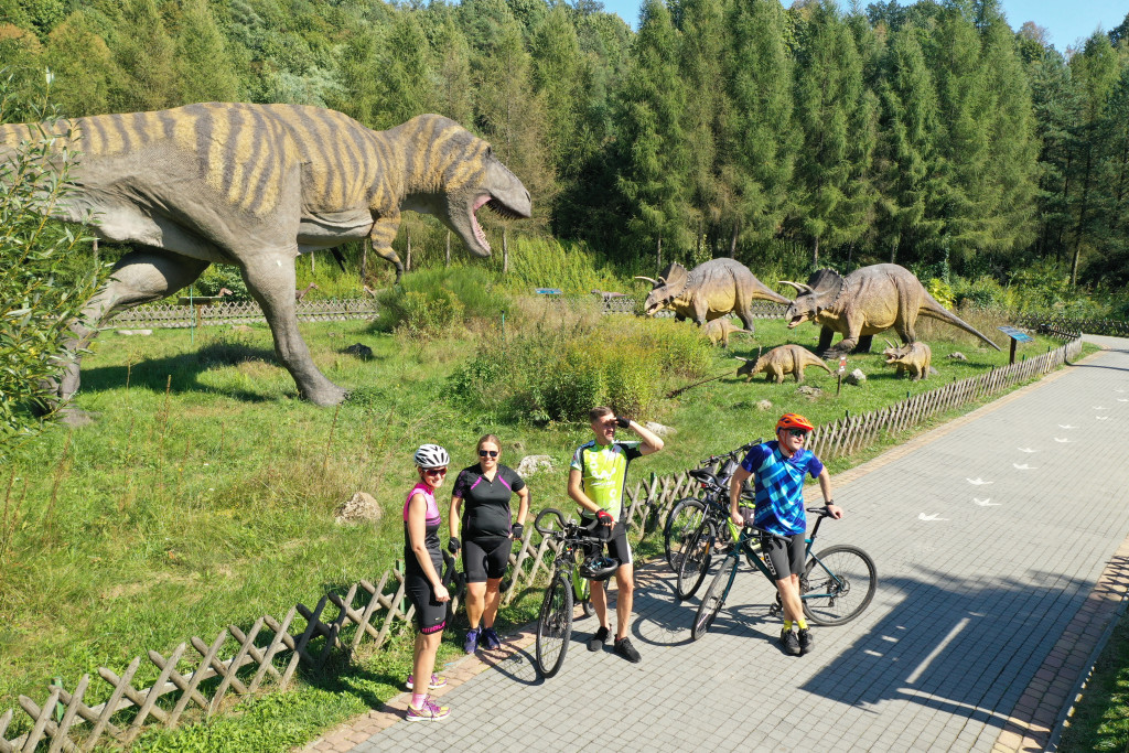 Rowerzyści oglądający modele dinozaurów w Bałtowskim Kompleksie Turystycznym