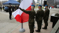 Żołnierze stoją przed masztem z polską flagą