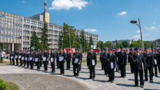 Kilkudziesięciu Strażaków Stoi W Równych Rzędach Przed Urzędem Wojewódzkim Trzymając W Rękach Akty Zakupu Samochodów I Promesy Na Zakup Samochodów Strażackich