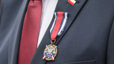 Zdjęcie zbliżenie, na Medal w butonierce marynarki marszałka Andrzeja Bętkowskiego. Nad medalem flaga Polski