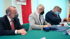 Wójtowie gmin siedzą przy stole i w obecności wicemarszałka Marka Bogusławskiego podpisują porozumienie