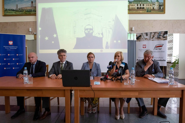 Za stołem siedzi kilka osób. Wśród nich przemawiająca z mikrofonem wicemarszałek Renata Janik