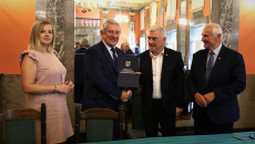 Marszałek Andrzej Bętkowski i członek Zarządu Województwa Marek Jońca gratulują mężczyźnie w ciemnym garniturze, białej koszuli i ciemnym krawacie