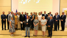 Szerokie zdjęcie, grupa osób stoi na podeście w sali kameralnej Filharmonii w Kielcach. Beneficjenci środków unijnych pozują do pamiątkowego zdjęcia
