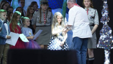 Scena amfiteatru, wicemarszałek Marek Bogusławski wręcza Jodłę młodej dziewczynce. Za dziewczynką stoją dzieci i młodzież, niektórzy ubrani w harcerski mundurek
