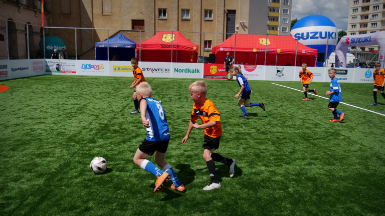 Dziecięce drużyny piłkarskie grają na ogrodzonym boisku do gry w piłkę nożną