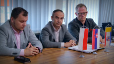 Trzech mężczyzn w garniturach siedzi przy stole w sali konferencyjnej. Na stole małe flagi Polski, Słowacji i Województwa Świętokrzyskiego. Jeden z mężczyzn to dyrektor Piotr Kisiel