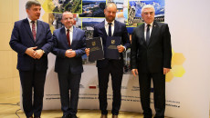 Urzędnik z gminy Działoszyce na fotografii z przedstawicielami samorządu województwa świętokrzyskiego, prezentuje okolicznościowe dyplomy