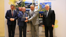 Urzędnik z gminy Imielno na fotografii z przedstawicielami samorządu województwa świętokrzyskiego, prezentuje okolicznościowy dyplom