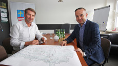 Dwóch mężczyzn siedzi przy stole, na stole kolorowa mapa