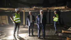 Marszałek Andrzej Bętkowski w towarzystwie pracowników firmy budowlanej, z poziomu dawnej sceny teatru obserwuje postęp prac. Scenę oświetla tylko jedna lampa budowlana