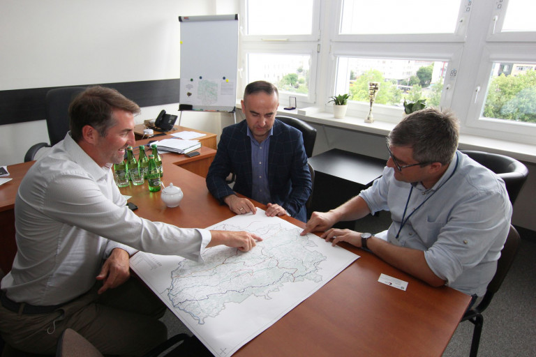 Wskazując miejsca na mapie trzech mężczyzn dyskutuje na temat przebiegu tras rowerowych