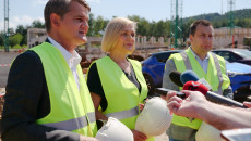 Grupa osób na budowie. Po środku wicemarszałek Renata Janik, trzyma kask chroniący głowę. W tle filary konstrukcji nowobudowanego budynku