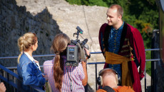 Zdjęcie zbliżenie na ekipę TVP 2 w rozmowie z Konradem Szymańskim, Przewodnikiem ubranym w kostium historyczny, zachęcającym do zwiedzania Zamku w Chęcinach