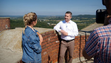 Radny województwa świętokrzyskiego Marcin Piętak opowiada o regionie stojąc na wieży Zamku. Rozmowę z prowadzącą program filmuje kamerzysta