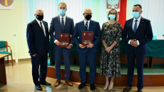 Grupa osób pozuje do pamiątkowej fotografii. Dwóch mężczyzn trzyma podpisane umowy. Pierwszy z lewej to Andrzej Bętkowski, marszałek województwa