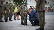 Kielce, plac Wolności. Uczestnicząca w marszu, mała dziewczynka ubrana w mundur, odbiera odznaczenie od klęczącego przed nią szefa Urzędu do Spraw Kombatantów i Osób Represjonowanych