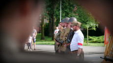 Uczestnicy Rekonstrukcji Historycznej stoją na placu. Widok przez tunel w kształcie trójkąta