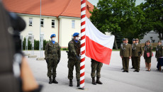Dwóch żołnierzy przy biało czerwonym wysokim słupie. Wciągnięcie Flagi