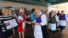 Na scenie grupa kobiet w strojach ludowych. Wicemarszałek Renata Janik Gratuluje Jaworzankom Wyróżnienia