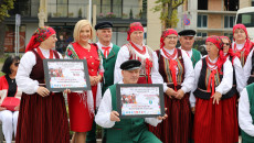 Grupa artystów ludowych uśmiecha się stojąc przed siedzibą WDK w Kielcach. Wicemarszałek Renata Janik z Członkami Kapeli Chełmowianie