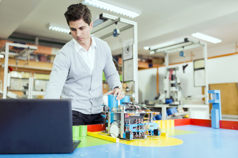 Electrical Engineer Programming A Robot During Robotics Class