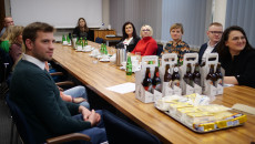 Na stole butelki z piwem, które ma być wpisane na listę Dziedzictwa Kulinarnego, przy stole siedzą uczestnicy spotkania