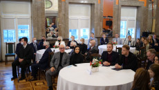 Grupa laureatów Talentów Świętokrzyskich siedzi za stołem w sali WDK
