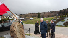 Andrzej Bętkowski wśród grupy osób stojących przed pomnikiem poświęconym rozstrzelanym mieszkańców Huty Szklanej