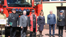 Samorządowcy i posłanka Agata Wojtyszek stoją obok wozu strażackiego z kapelanem strazaków