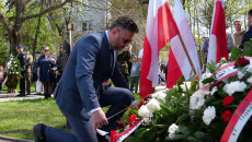 Tomasz Jamka, członek Zarządu Województwa Świetokrzyskiego klęczy przed pomnikiem powstańców