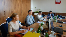 Człnokowie komisji siedzą przy stole obrad