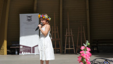 dziewczynka z wiankiem na głowie śpiewa na scenie