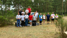 Czworo Zawodników Stoi Na Podium. Obok Podium Stoi Grupa Ludzi