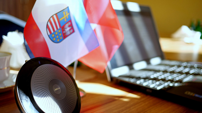 Flagi z herbem województwa świętokrzyskiego, otwarty laptop oraz głośnik