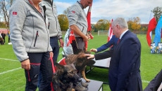 Andrzej Bętkowski głaszcze siedzącego na podium psa. Na podium stoją także zwycięzcy Mistrzostw.