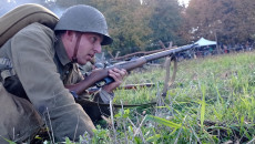 Mężczyzna W Pozycji Leżącej Na Trawie Z Bronią Długą