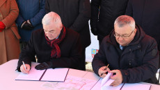 Andrzej Bętkowski i minister infrastruktury Andrzej Adamczyk podpisują umowę siedząc przy stole na dworze we Włoszczowie