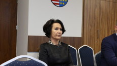 Dyrektor Elzbieta Korus siedzi na tle herbu województwa