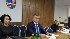 Dyrektor Rafał Kosiński siedzi na tle brązowej szafy