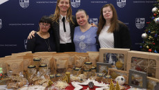 Opiekun i podopieczne Zakładu Aktywności Zawodowej Manufaktura Pietraszki pozują do zdjęcia z własnoręcznie wykonanymi świątecznymi ozdobami