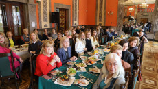 Dwa długie stoły zastawione potrawami a przy nich siedzą obywatele Ukrainy