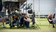 Technik filmowy siedzi pod namiotem otoczony sprzętem filmowym