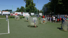 Dzieci biegają po boisku w pompowanych plastikowych kulach