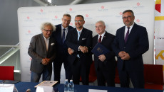 Andrzej Mochoń, Bogdan Wenta, konsul, Andrzej Bętkowski i Tomasz Jamka stoją za stołem po podpisaniu porozumienia i ściskają sobie dłonie