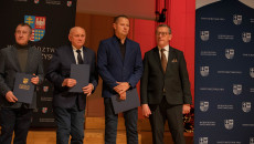 Henryk Milcarz stoi na scenie wraz z nagrodzonym sportowcem i jego trenerem