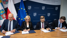 Strony podpisują umowę siedząc za stołem